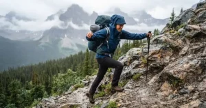 Hiker wearing a fitted waterproof rain jacket navigating steep, technical terrain safely without snagging hazards.