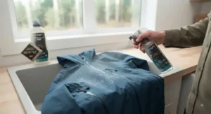 Applying a fresh durable water repellent spray to a damp jacket to restore water beading on the outer shell.