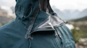 Close-up of a fully taped waterproof zipper and helmet-compatible hood on a high-performance rain jacket for Canadian Rockies climbing.